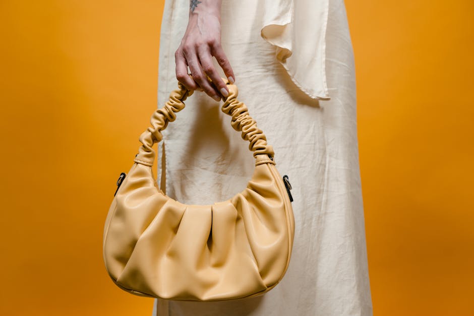 Stylish yellow handbag held against a vibrant background, perfect for fashion themes.